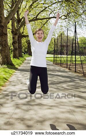 Stock Photo - A young woman jumping up in joy. Fotosearch