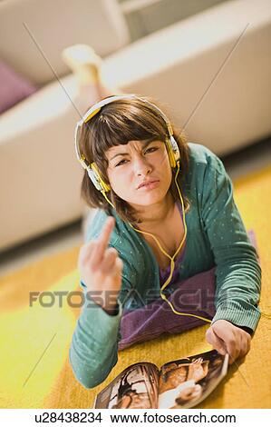 Picture - Angry girl with headphones and magazine. Fotosearch