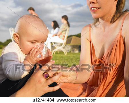 Picture - baby drinking out of mothers glass. Fotosearch