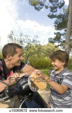 Stock Image - boy and dad washing a scooter. Fotosearch
