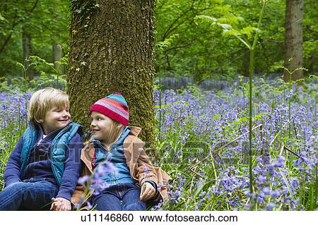 Boy and Girl sitting against a tree View Large Photo Image Stock Image - Boy and Girl sitting against a tree. Fotosearch