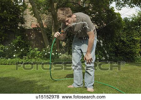 Stock Photo - Boy drinking water from hosepipe. Fotosearch
