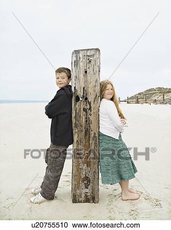 Stock Image - Boy & Girl leaning against post. Fotosearch