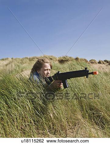 Stock Image - Boy in dunes with toy gun. Fotosearch