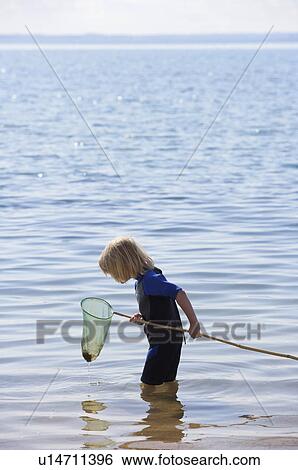Boy look into a fishing net View Large Photo Image Stock Photograph - Boy look into a fishing net. Fotosearch
