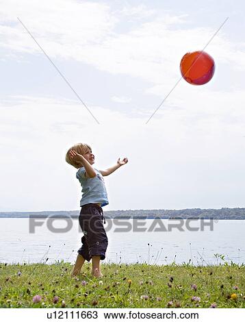 Stock Image - boy playing with ball at lake. Fotosearch