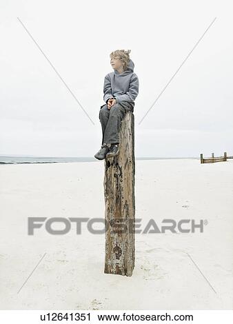 Stock Image - Boy sitting on top of post. Fotosearch