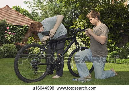 Boys fixing bicycle together View Large Photo Image Stock Photo - Boys fixing bicycle together. Fotosearch