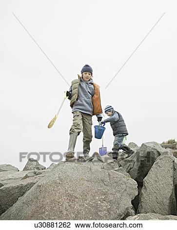 Boys on beach rocks View Large Photo Image Stock Image - Boys on beach rocks. Fotosearch