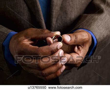 Stock Image - Business man holding wedding band. Fotosearch