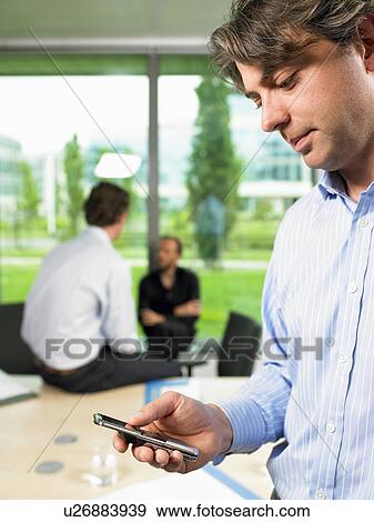Stock Photo - Business man looking at his phone. Fotosearch