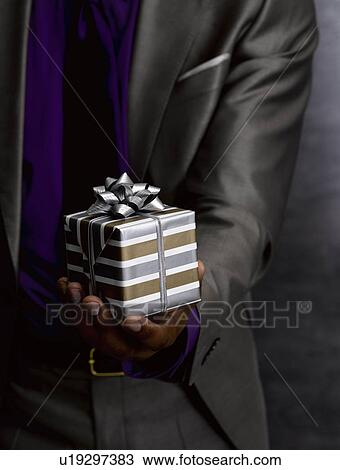 Stock Image - Business man offering gift. Fotosearch