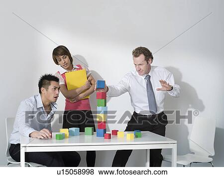 Stock Photo - Business man puts last block on tower. Fotosearch