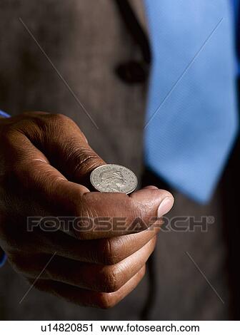 Stock Image - Business man ready to flip sterling coin. Fotosearch