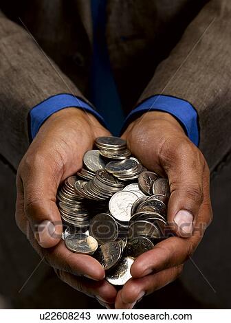 Stock Image - Business man with handful of coins. Fotosearch