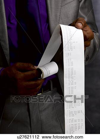 Stock Image - Business man with long paper receipt. Fotosearch