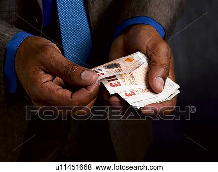 Stock Photo - Business man with wad of sterling notes. Fotosearch