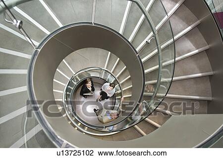 Stock Image - Business trio in a spiral stairwell. Fotosearch