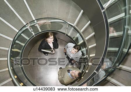 Stock Image - Business trio in a spiral stairwell. Fotosearch