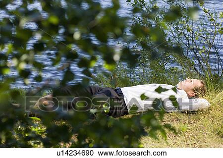 Stock Image - businessman relaxing on lakefront. Fotosearch