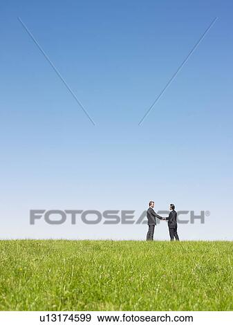businessmen shaking hands in field View Large Photo Image Stock Photo - businessmen shaking hands in field. Fotosearch