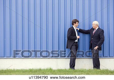 Stock Image - businessmen talking in front of storage. Fotosearch