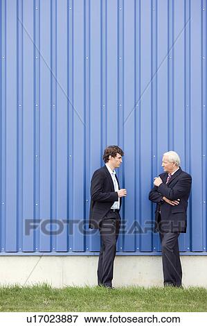 Stock Photo - businessmen talking in front of storage. Fotosearch
