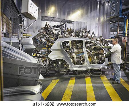 Stock Image - Car Plant Worker Assembling Car. Fotosearch