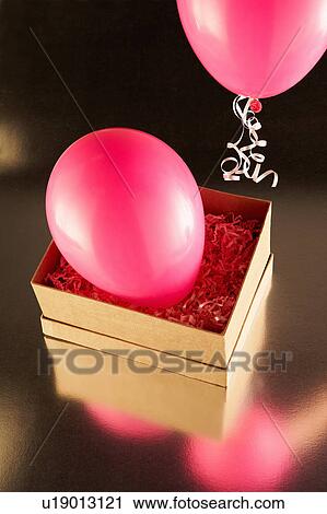 Stock Image - Cardboard box with pink party balloons. Fotosearch