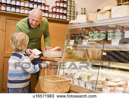 Stock Image - cheese store owner with boy in shop. Fotosearch