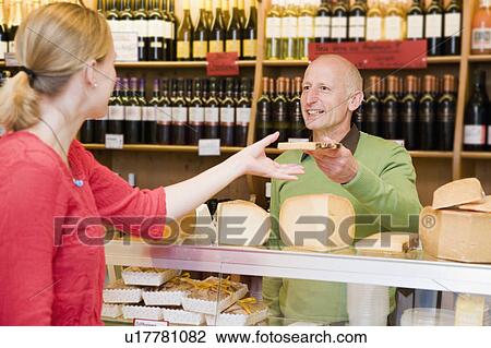 Stock Image - cheese store owner with customer in shop. Fotosearch