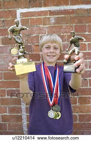 Picture - Child footballer with medals and trophy. Fotosearch