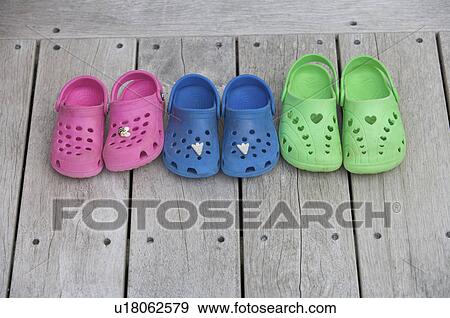 Stock Photo - Childrens shoes on wooden decking. Fotosearch