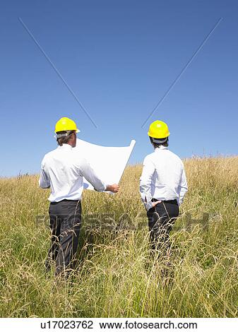 Stock Image - contractors with blueprints in field. Fotosearch