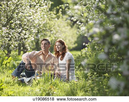 Stock Photo - Couple Having Picnic In Orchard. Fotosearch
