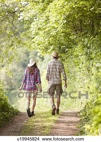 Picture - couple in hats walking along track. Fotosearch