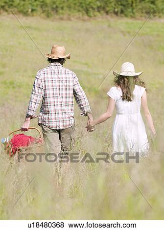 couple in hats walking through meadow View Large Photo Image Stock Photo - couple in hats walking through meadow. Fotosearch