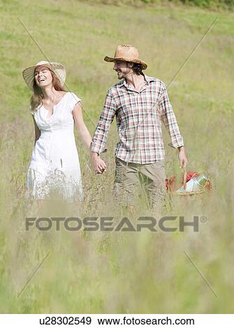 couple in hats walking through meadow View Large Photo Image Stock Photo - couple in hats walking through meadow. Fotosearch