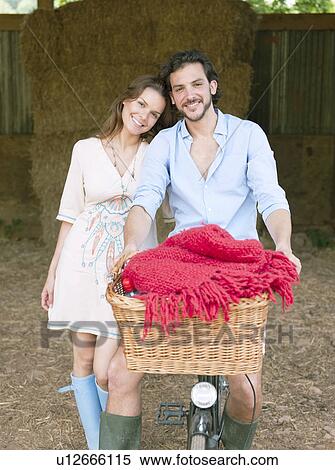 Couple in on bike with picnic basket View Large Photo Image Stock Photography - Couple in on bike with picnic basket. Fotosearch
