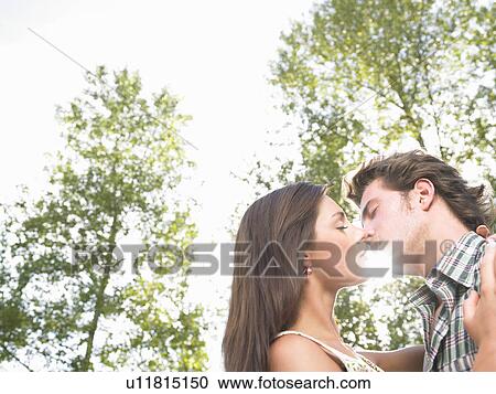 Stock Image - couple kissing under trees. Fotosearch