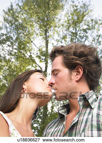 Stock Photo - couple kissing under trees. Fotosearch