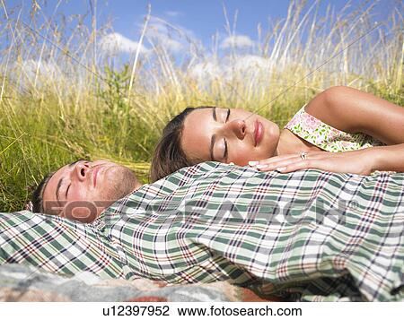 Stock Image - couple lying in field of high grasses. Fotosearch