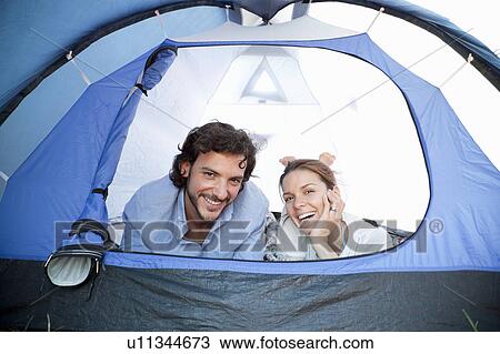 Stock Image - Couple lying in tent smiling. Fotosearch