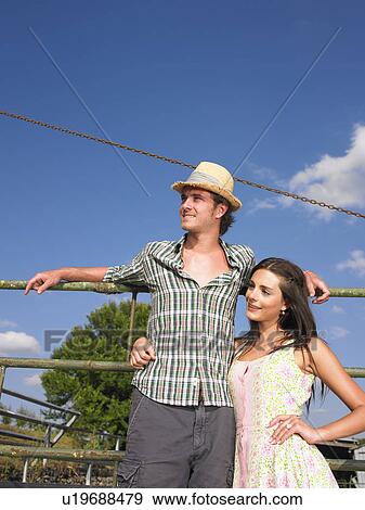 Stock Photo - couple posing on farm gate. Fotosearch