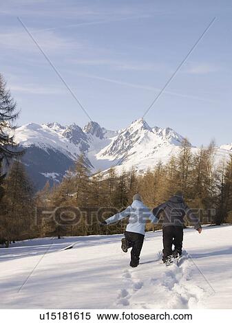 couple running in snow towards mountain View Large Photo Image Stock Photography - couple running in snow towards mountain. Fotosearch
