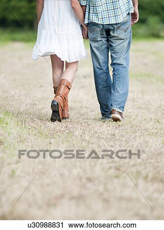 Stock Image - Couple walking in countryside field. Fotosearch