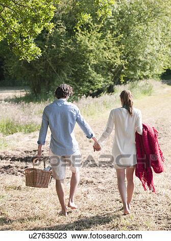 Couple walking in field with picnic View Large Photo Image Stock Image - Couple walking in field with picnic. Fotosearch