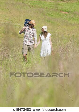Stock Image - couple walking through long grass. Fotosearch