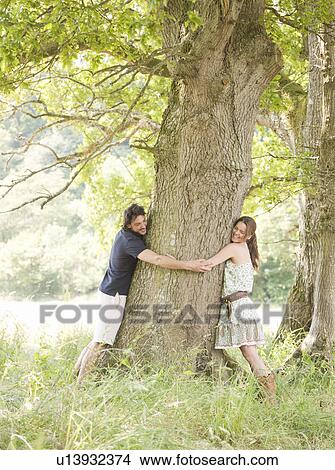 Picture - couple with arms around tree. Fotosearch