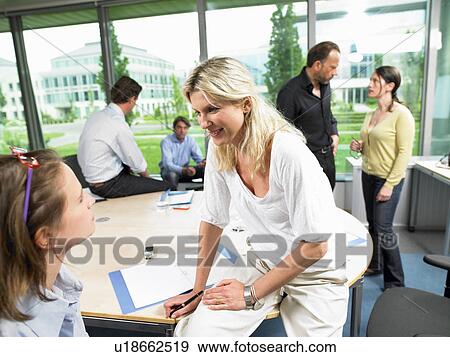 Stock Photo - Coworkers in the office, talking. Fotosearch